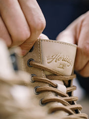 製品画像: 厳選された牛革スエードと特注厚底デザインを組み合わせたヴィンテージ感漂うワークブーツ全体像、グラベルカラーのトーンが特徴。
詳細画像: 牛革スエードのアッパー、PUレザー靴舌、白いステッチが際立つラバーディテールのクローズアップ。