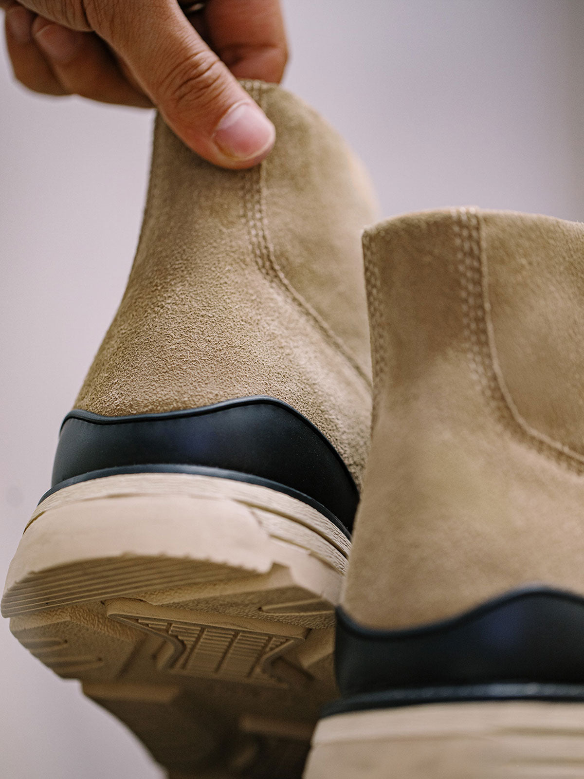 製品画像: 厳選された牛革スエードと特注厚底デザインを組み合わせたヴィンテージ感漂うワークブーツ全体像、グラベルカラーのトーンが特徴。
詳細画像: 牛革スエードのアッパー、PUレザー靴舌、白いステッチが際立つラバーディテールのクローズアップ。