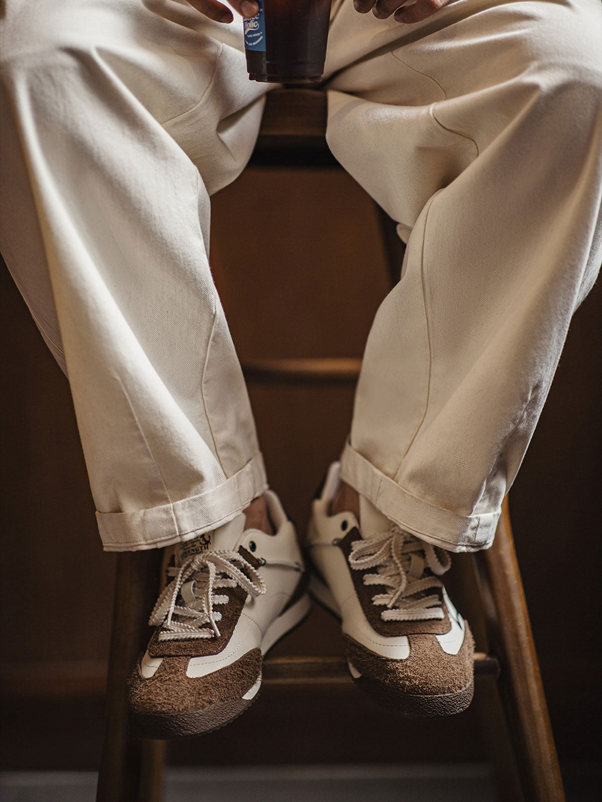 詳細画像: 60Sピースバスケットシューズのアッパー部分、長毛感のあるスエード革と異素材のコンビネーションが美しく融合し、レトロ感を強調しています。金色のレトロ金属刻印と刺繍のディテールがシューズに高級感を与えています。
モデル画像: モデルが60Sピースバスケットシューズを着用している画像。レトロなデザインと現代的な改良が調和したシューズが、クラシックでありながらも個性的なスタイルを演出し、日常のコーディネートにぴったりです。