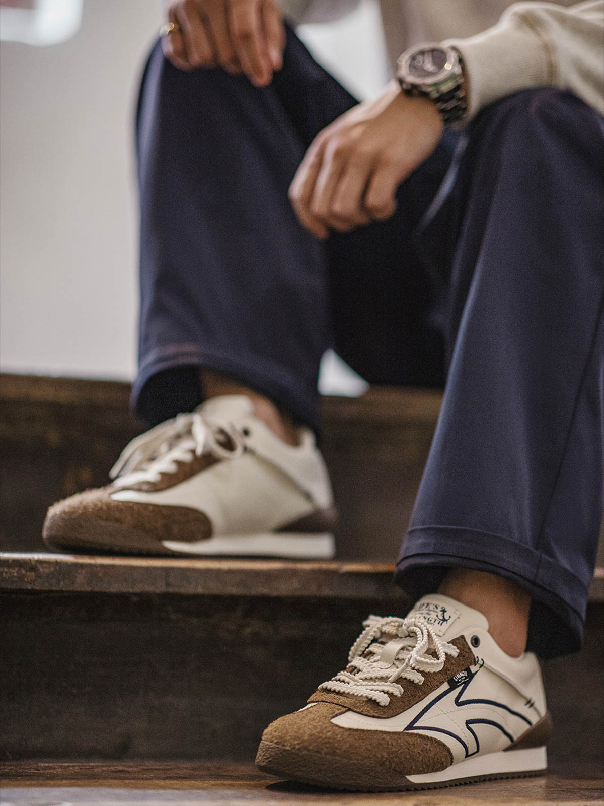 詳細画像: 60Sピースバスケットシューズのアッパー部分、長毛感のあるスエード革と異素材のコンビネーションが美しく融合し、レトロ感を強調しています。金色のレトロ金属刻印と刺繍のディテールがシューズに高級感を与えています。
モデル画像: モデルが60Sピースバスケットシューズを着用している画像。レトロなデザインと現代的な改良が調和したシューズが、クラシックでありながらも個性的なスタイルを演出し、日常のコーディネートにぴったりです。