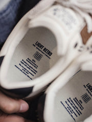 製品画像: 60Sピースバスケットシューズ正面展示画像。長毛感のあるスエード革と異素材のコンビネーションが特徴で、ネイビーブルーのエレクトリック刺繍矢印ロゴがサイドに配置されています。ヒール部分にはブラックの本革と金色のレトロな金属刻印が施され、独自のデザインを際立たせています。
詳細画像: 60Sピースバスケットシューズのアッパー部分、長毛感のあるスエード革と異素材のコンビネーションが美しく融合し、レトロ感を強調しています。金色のレトロ金属刻印と刺繍のディテールがシューズに高級感を与えています。