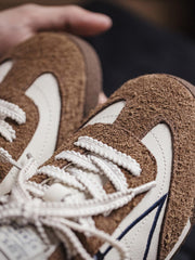 製品画像: 60Sピースバスケットシューズ正面展示画像。長毛感のあるスエード革と異素材のコンビネーションが特徴で、ネイビーブルーのエレクトリック刺繍矢印ロゴがサイドに配置されています。ヒール部分にはブラックの本革と金色のレトロな金属刻印が施され、独自のデザインを際立たせています。
詳細画像: 60Sピースバスケットシューズのアッパー部分、長毛感のあるスエード革と異素材のコンビネーションが美しく融合し、レトロ感を強調しています。金色のレトロ金属刻印と刺繍のディテールがシューズに高級感を与えています。