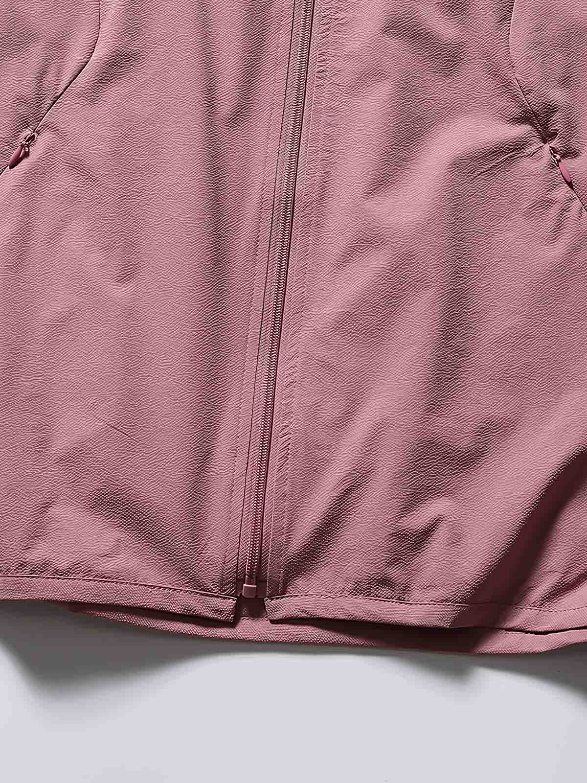 製品画像: フード付きアウトドア機能ベストの正面ビュー、軽量でシンプルなデザインが特徴。アウトドアにもカジュアルにも使えるアイテム。
詳細画像: フードと大きなポケット、防風・防水設計が強調されたディテールショット。耐久性のあるポリエステル素材が確認できる。