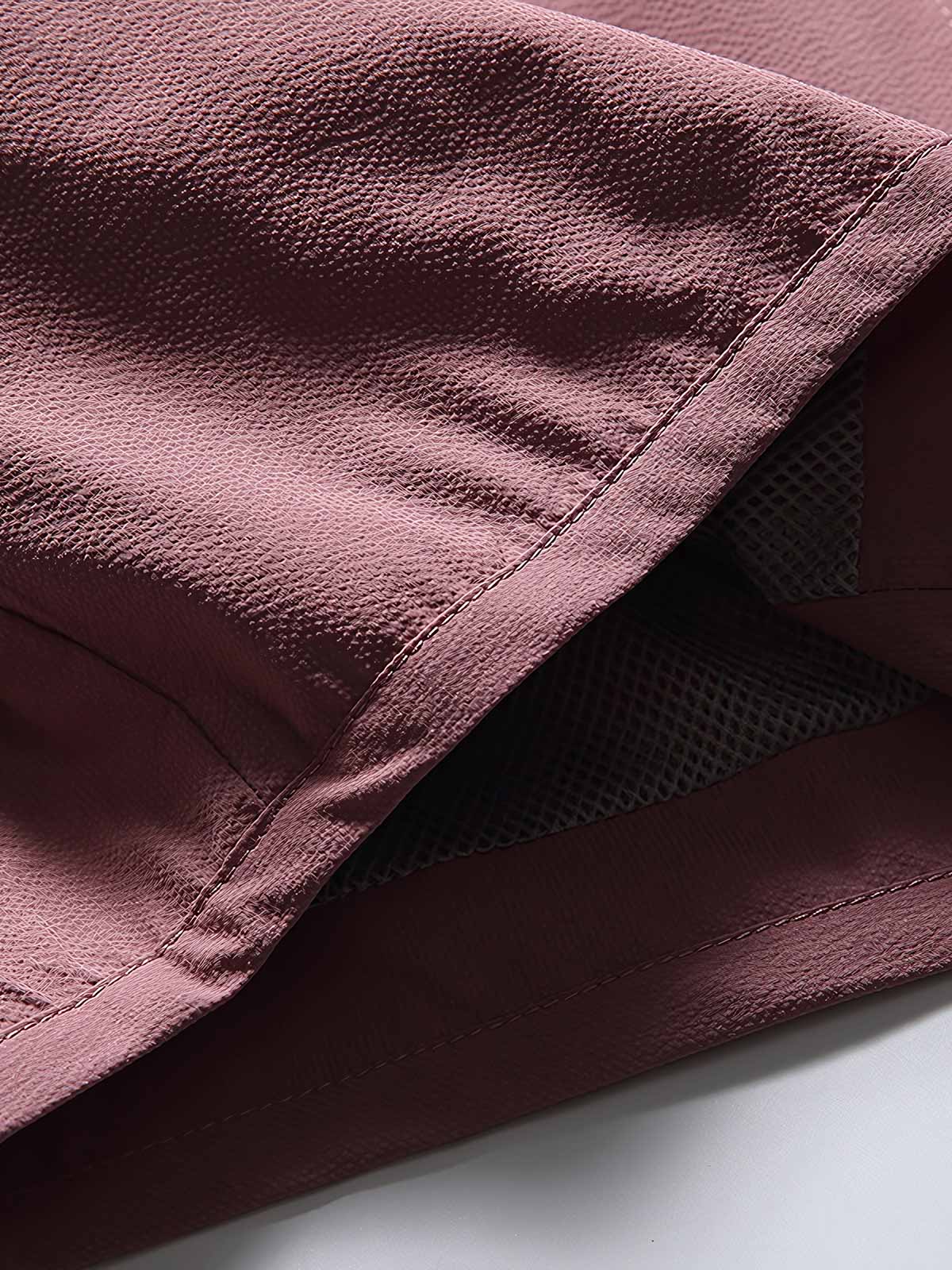 製品画像: フード付きアウトドア機能ベストの正面ビュー、軽量でシンプルなデザインが特徴。アウトドアにもカジュアルにも使えるアイテム。
詳細画像: フードと大きなポケット、防風・防水設計が強調されたディテールショット。耐久性のあるポリエステル素材が確認できる。