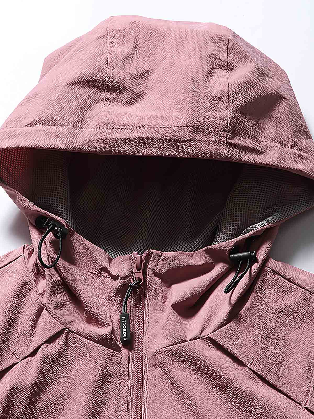 製品画像: フード付きアウトドア機能ベストの正面ビュー、軽量でシンプルなデザインが特徴。アウトドアにもカジュアルにも使えるアイテム。
詳細画像: フードと大きなポケット、防風・防水設計が強調されたディテールショット。耐久性のあるポリエステル素材が確認できる。