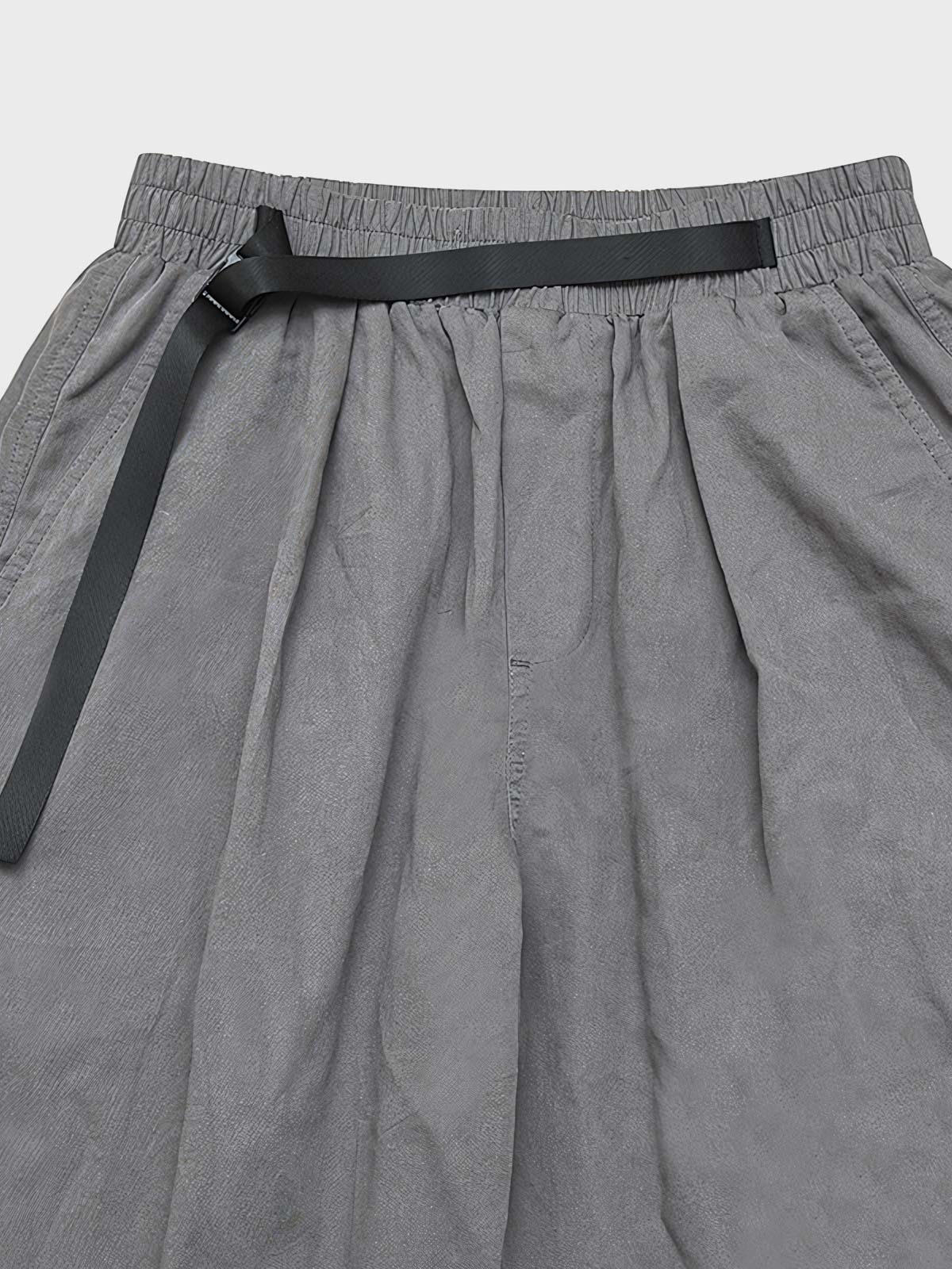 カジュアルパンツのドローコードとパッチワークディテールのクローズアップ。素材の耐久性と細部の工夫が見て取れる、機能的でスタイリッシュなデザイン。