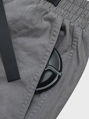 カジュアルパンツのドローコードとパッチワークディテールのクローズアップ。素材の耐久性と細部の工夫が見て取れる、機能的でスタイリッシュなデザイン。