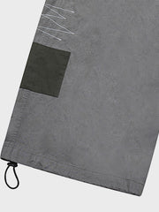 カジュアルパンツのドローコードとパッチワークディテールのクローズアップ。素材の耐久性と細部の工夫が見て取れる、機能的でスタイリッシュなデザイン。