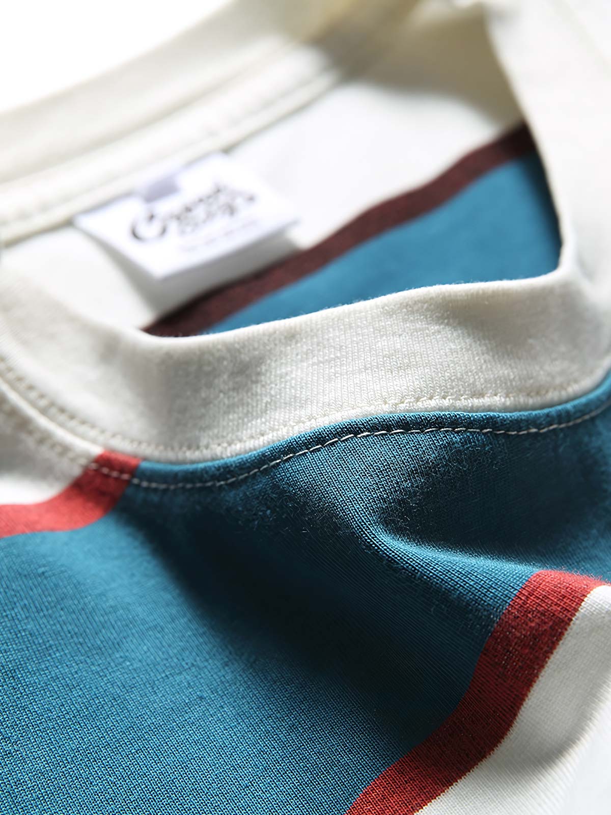 純綿素材のブルー&ホワイトストライプTシャツのクローズアップ。通気性と吸湿性に優れ、胸元のアルファベットプリントが洗練されたデザインアクセントを提供