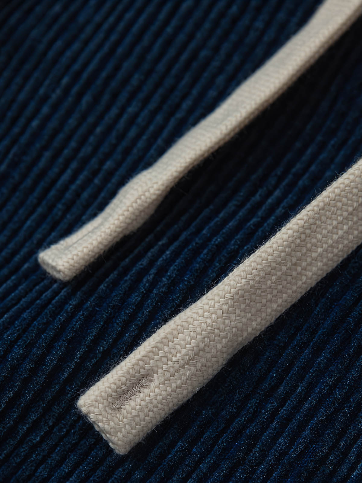 製品画像:
"水洗ヴィンテージ加工を施したデニムブルーの粗畝コーデュロイワークパンツ、秋冬シーズンにぴったりな重厚感のある素材とレトロな雰囲気が特徴の全体図"
詳細画像:
"粗畝コーデュロイ素材の肌理感とドローストリング仕様のウエスト部分をクローズアップした画像、ヴィンテージ加工による深みのあるデニムブルーが際立つディテール"