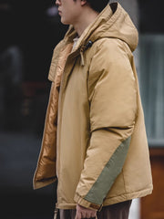 詳細画像
マットな光沢のナイロン生地、取り外し可能な防風フード、裾のエラスティックドローコードが実用性を高め、寒風を防ぎます。多層構造でダウンの膨らみを保ちつつ、優れた保温性を発揮します。シンプルでスリムなラインが特徴。
モデル画像
ECWCS L7スタイルのフード付きダウンジャケットを着用したモデル、冬の寒さにも対応できる優れた保温性とスタイリッシュなデザインが際立つ。