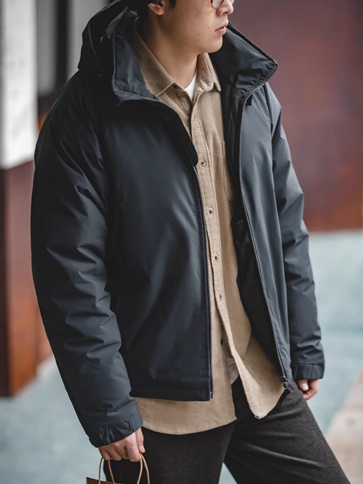 詳細画像
マットな光沢のナイロン生地、取り外し可能な防風フード、裾のエラスティックドローコードが実用性を高め、寒風を防ぎます。多層構造でダウンの膨らみを保ちつつ、優れた保温性を発揮します。シンプルでスリムなラインが特徴。
モデル画像
ECWCS L7スタイルのフード付きダウンジャケットを着用したモデル、冬の寒さにも対応できる優れた保温性とスタイリッシュなデザインが際立つ。