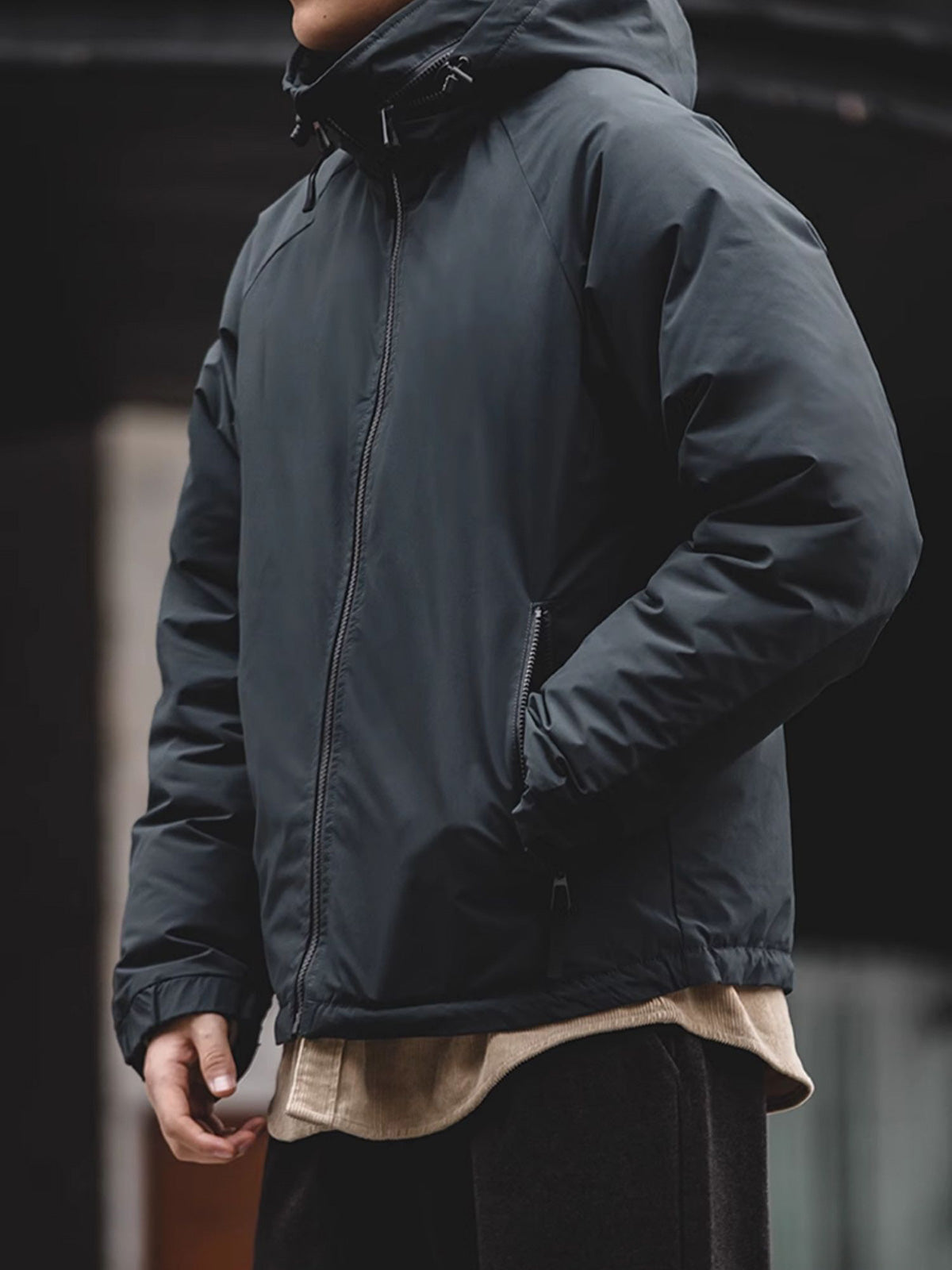 詳細画像
マットな光沢のナイロン生地、取り外し可能な防風フード、裾のエラスティックドローコードが実用性を高め、寒風を防ぎます。多層構造でダウンの膨らみを保ちつつ、優れた保温性を発揮します。シンプルでスリムなラインが特徴。
モデル画像
ECWCS L7スタイルのフード付きダウンジャケットを着用したモデル、冬の寒さにも対応できる優れた保温性とスタイリッシュなデザインが際立つ。