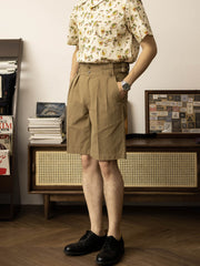 モデルが高腰ダブルプリーツ ワイドガーキショーツを着用し、シンプルな白Tシャツとカジュアルシューズでコーディネート。快適でスタイリッシュな夏のカジュアルルックを展示しています。