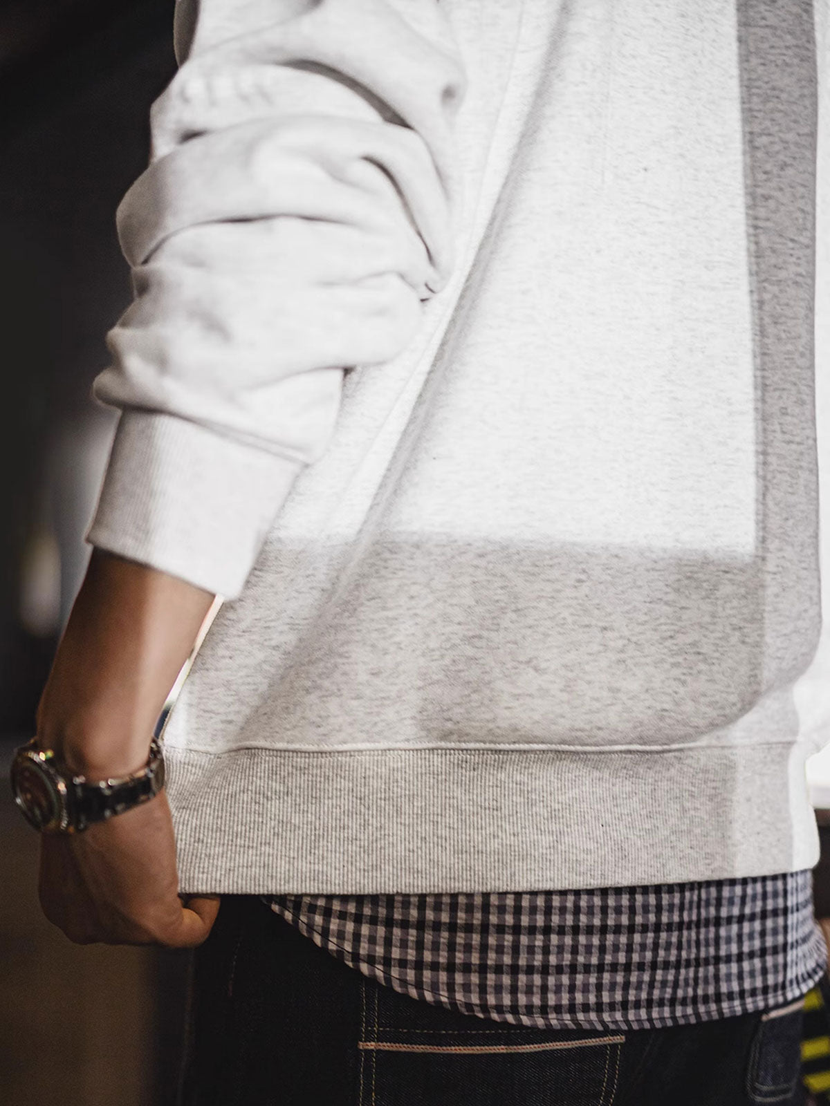 製品画像: ライトグレーの裏起毛クルーネックスウェット全体イメージ画像。リラックスシルエットとドロップショルダーデザインが特徴で、胸元には「ピースマーク」プリントがアクセント。単独でもインナーとしても活躍する秋冬の万能アイテム。
詳細画像: 胸元に配置された精巧な「ピースマーク」プリントとクラシックなリブ仕様のネックや裾をクローズアップした画像。保温性と耐久性を兼ね備えた裏起毛素材が際立つ。