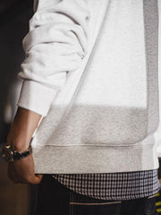 製品画像: ライトグレーの裏起毛クルーネックスウェット全体イメージ画像。リラックスシルエットとドロップショルダーデザインが特徴で、胸元には「ピースマーク」プリントがアクセント。単独でもインナーとしても活躍する秋冬の万能アイテム。
詳細画像: 胸元に配置された精巧な「ピースマーク」プリントとクラシックなリブ仕様のネックや裾をクローズアップした画像。保温性と耐久性を兼ね備えた裏起毛素材が際立つ。