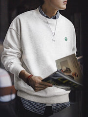 詳細画像: 胸元に配置された精巧な「ピースマーク」プリントとクラシックなリブ仕様のネックや裾をクローズアップした画像。保温性と耐久性を兼ね備えた裏起毛素材が際立つ。
モデル画像: 裏起毛クルーネックスウェットを着用したモデルが、スニーカーとブラックパンツを合わせたカジュアルな秋冬スタイルを提案。快適さと個性を両立したコーディネートが魅力的。