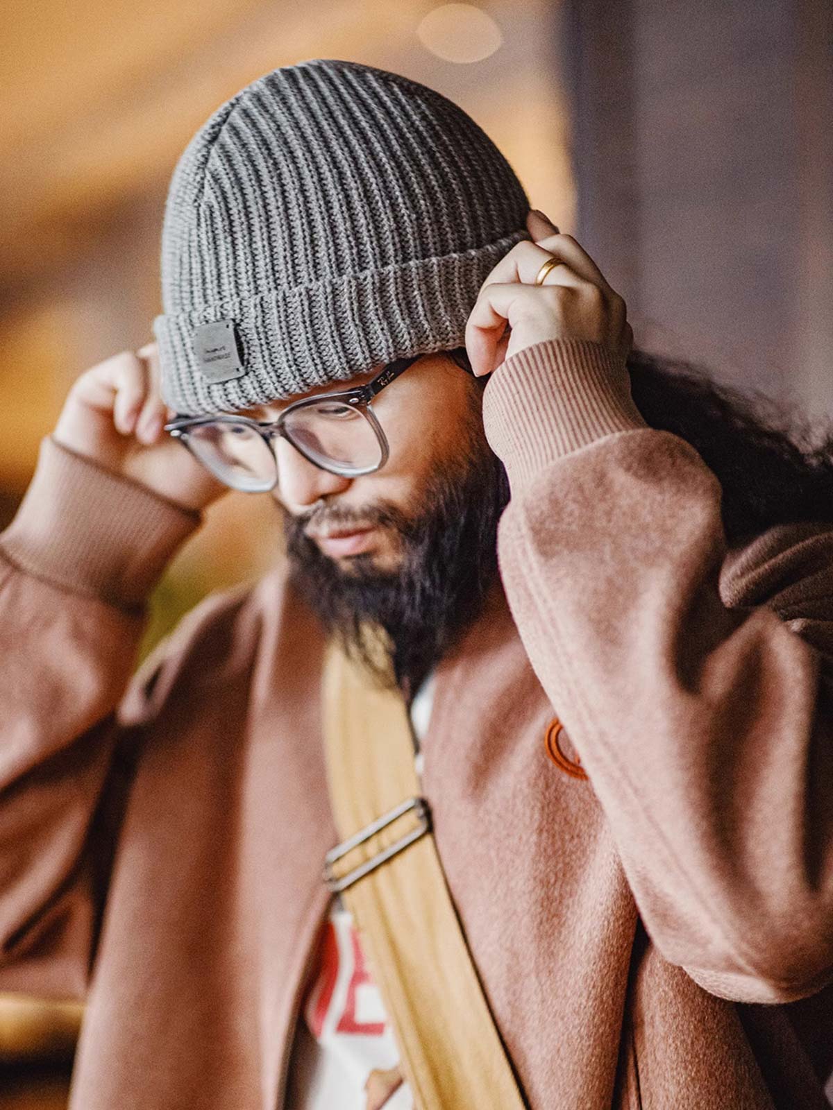 詳細画像: ハンドメイドのレザーパッチとクラシックなローゲージ編みディテール
モデル画像: 冬のヴィンテージストリートスタイルで着用されたローゲージニットキャップ