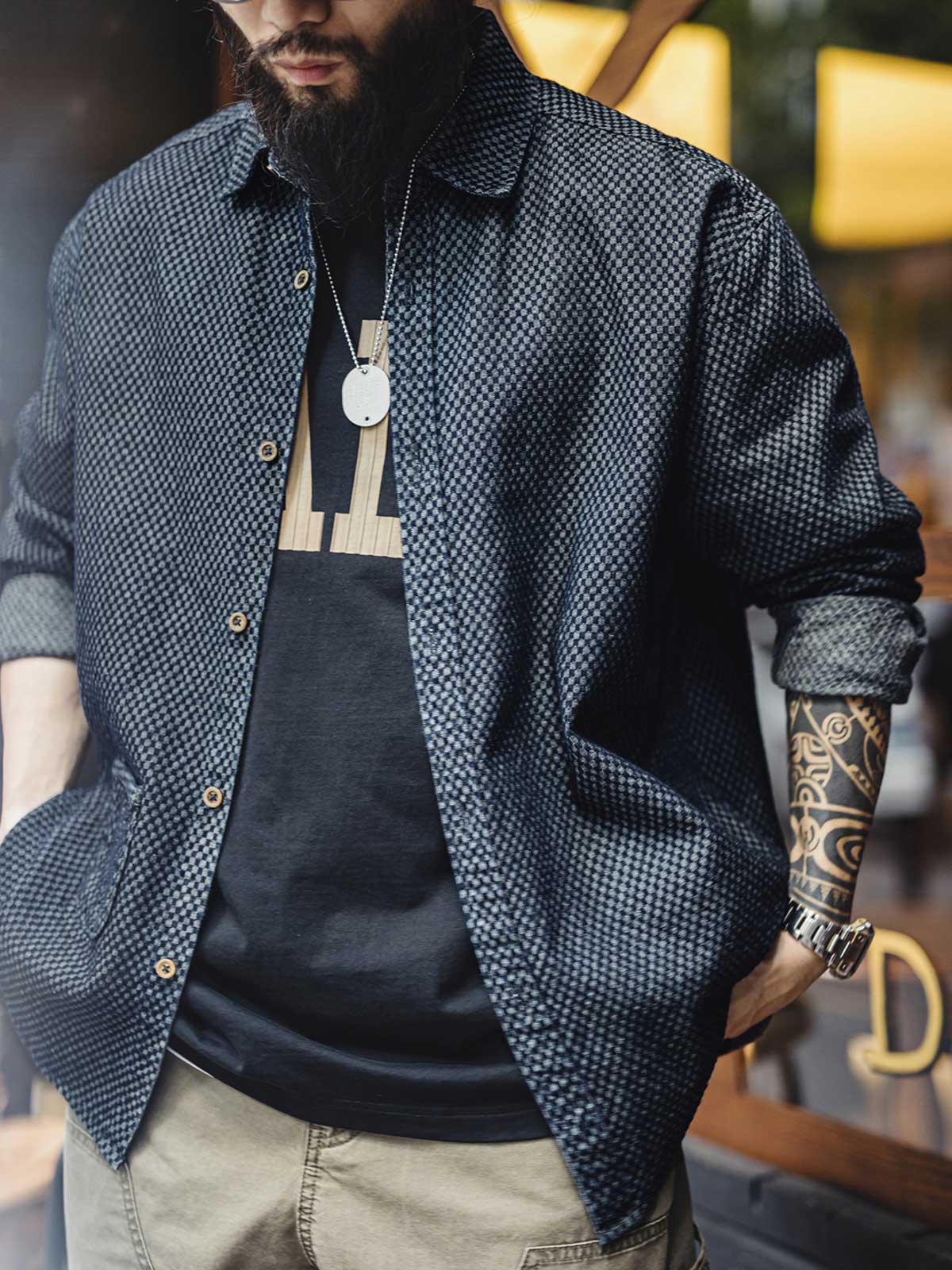 詳細画像
チェッカーボード柄のディテールと、しっかりとしたデニム生地の質感を強調した画像。耐久性のある縫製と、ボタンのディテールが特徴的。
モデル画像
チェッカーボードデニムシャツを着用したモデル。レトロストリートスタイルを体現し、カジュアルな日常シーンでのスタイリングを提案。