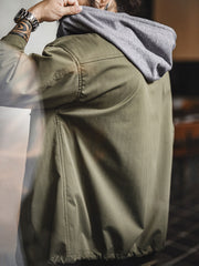 詳細画像
「耐久性に優れたヘリンボーン生地とヴィンテージ感を引き立てるレーザーボタン、明るいステッチラインのディテールをクローズアップした画像。」
モデル画像
「モデルがレイヤード風 パッチワーク フード付きワークジャケットを着用し、レトロなワークウェアと現代のアーバンスタイルを融合したコーディネートを披露。」