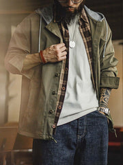 詳細画像
「耐久性に優れたヘリンボーン生地とヴィンテージ感を引き立てるレーザーボタン、明るいステッチラインのディテールをクローズアップした画像。」
モデル画像
「モデルがレイヤード風 パッチワーク フード付きワークジャケットを着用し、レトロなワークウェアと現代のアーバンスタイルを融合したコーディネートを披露。」