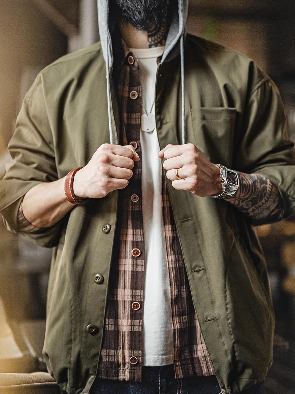 詳細画像
「耐久性に優れたヘリンボーン生地とヴィンテージ感を引き立てるレーザーボタン、明るいステッチラインのディテールをクローズアップした画像。」
モデル画像
「モデルがレイヤード風 パッチワーク フード付きワークジャケットを着用し、レトロなワークウェアと現代のアーバンスタイルを融合したコーディネートを披露。」