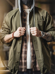 詳細画像
「耐久性に優れたヘリンボーン生地とヴィンテージ感を引き立てるレーザーボタン、明るいステッチラインのディテールをクローズアップした画像。」
モデル画像
「モデルがレイヤード風 パッチワーク フード付きワークジャケットを着用し、レトロなワークウェアと現代のアーバンスタイルを融合したコーディネートを披露。」