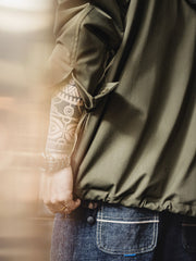 詳細画像
「耐久性に優れたヘリンボーン生地とヴィンテージ感を引き立てるレーザーボタン、明るいステッチラインのディテールをクローズアップした画像。」
モデル画像
「モデルがレイヤード風 パッチワーク フード付きワークジャケットを着用し、レトロなワークウェアと現代のアーバンスタイルを融合したコーディネートを披露。」