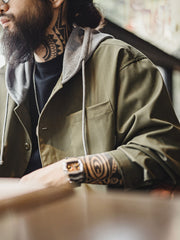 詳細画像
「耐久性に優れたヘリンボーン生地とヴィンテージ感を引き立てるレーザーボタン、明るいステッチラインのディテールをクローズアップした画像。」
モデル画像
「モデルがレイヤード風 パッチワーク フード付きワークジャケットを着用し、レトロなワークウェアと現代のアーバンスタイルを融合したコーディネートを披露。」