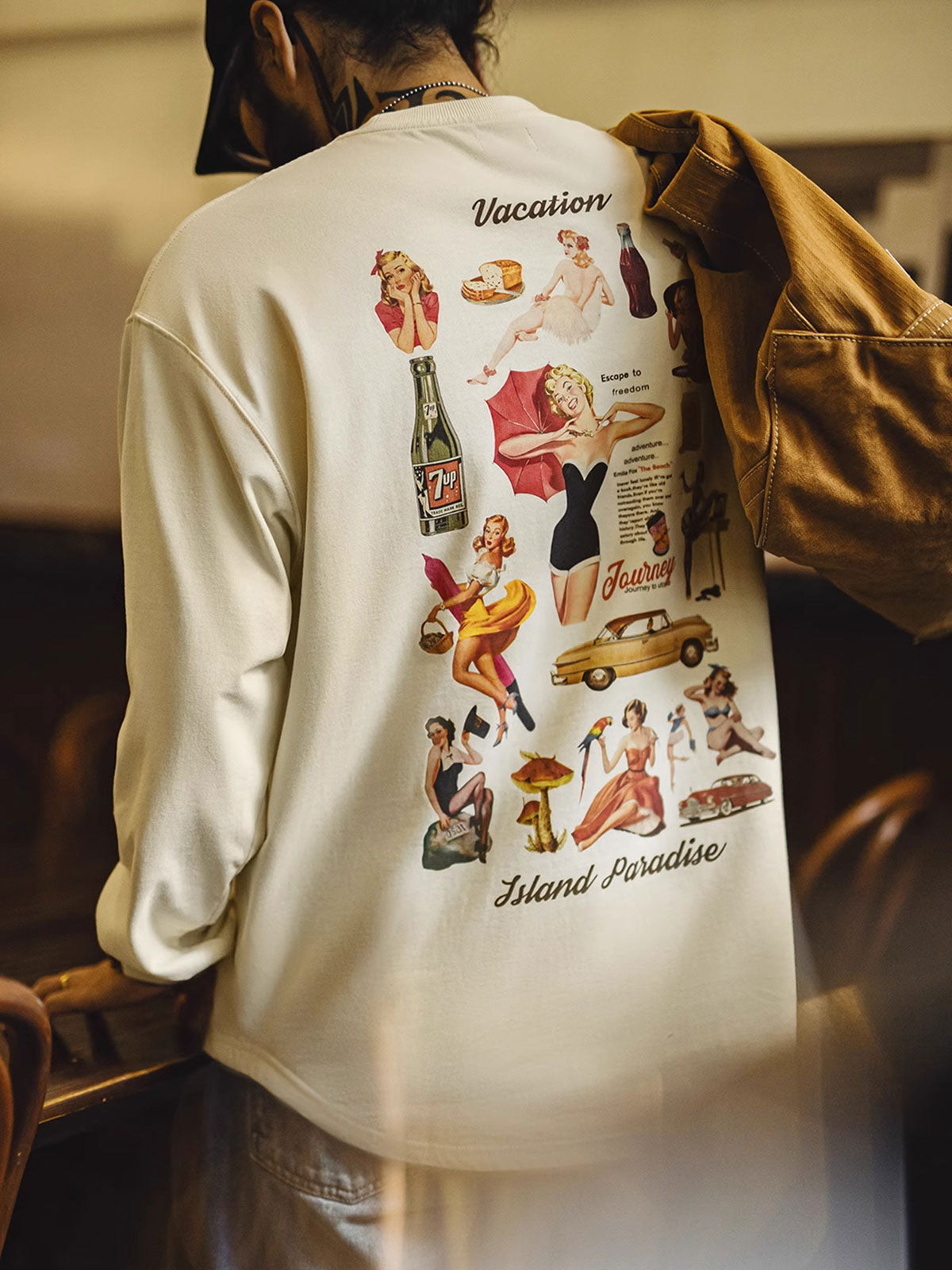 詳細画像
60年代ピンナップガールとクラシックカーをモチーフにしたポスター風プリントのディテール。高品質コットン生地に施された精巧な印刷が魅力
モデル画像
ホリデータイムにぴったりなレトロプリントTシャツを着たモデルが、デニムパンツと合わせたカジュアルスタイルを披露。リラックス感のある着心地が特徴