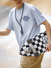 モデルが着用する「BRAVE MOUNTAIN ATHLETIC CLUB」プリントのマカロンカラーTシャツ、リラックスしつつ洗練されたフィット感を示す。