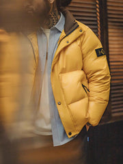 詳細画像
六角形ジッパーチャームとインディアン柄刺繍ディテール、鮮やかなイエローが際立つデザイン、防水加工されたナイロン素材とレトロなディテールのクローズアップ
モデル画像
80年代のストリートカルチャーを反映したイエローダウンジャケットを着用したモデル、高襟デザインと鮮やかなカラーが目を引く、街中のストリートスタイルを表現