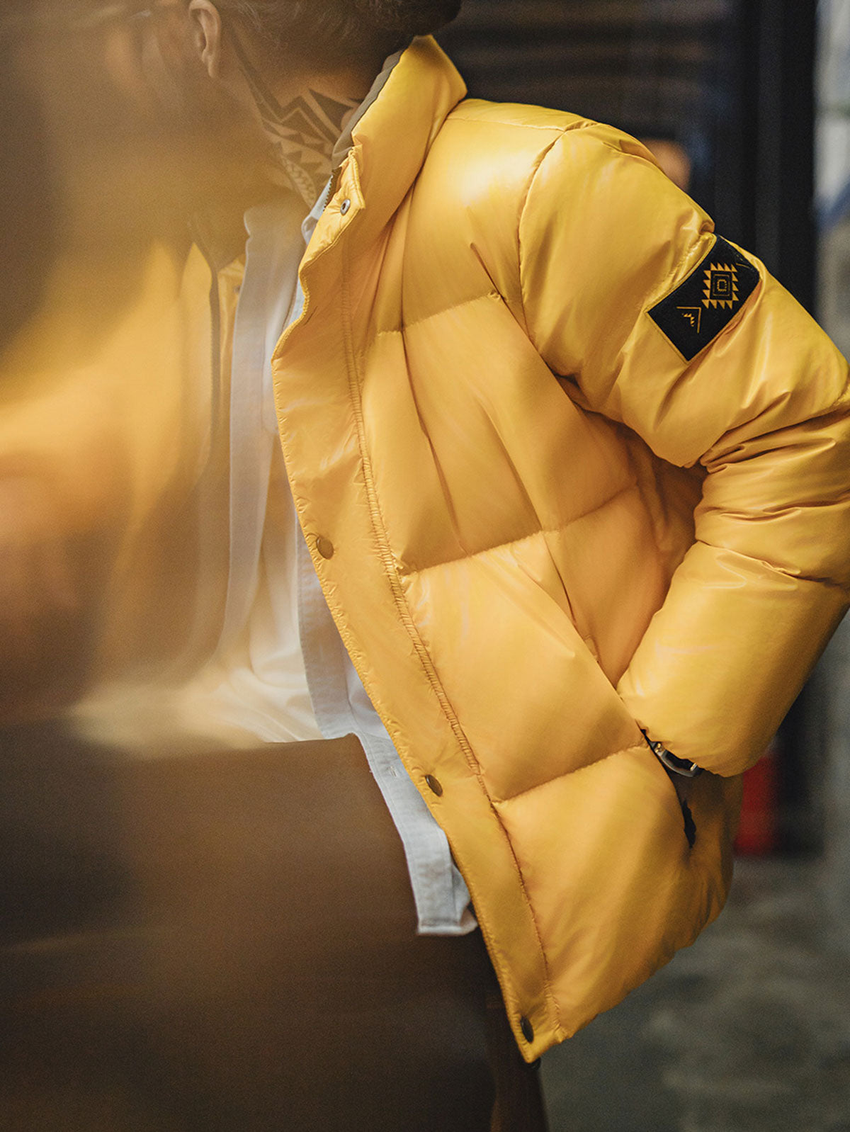 製品画像
鮮やかなイエローのハイカラー・ダウンジャケット、80年代のパニナーロスタイルを再現、撥水性4級のナイロン防水素材、クラシックなデザインと高襟が特徴のジャケット
詳細画像
六角形ジッパーチャームとインディアン柄刺繍ディテール、鮮やかなイエローが際立つデザイン、防水加工されたナイロン素材とレトロなディテールのクローズアップ