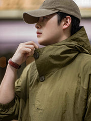 詳細画像
スタンドカラーと折り襟の2WAY仕様、エポレットディテール、フラップ付きスナップボタンポケット、そしてドローコード付き裾のディテールを強調したクローズアップ画像。機能性とデザイン性が融合した細部。
モデル画像
リラックス感のあるオーバーサイズシルエットのヴィンテージフード付きジャケットを着用し、アウトドアコーディネートを演出したモデル画像。軽量で耐久性のあるデザインが際立つスタイル。