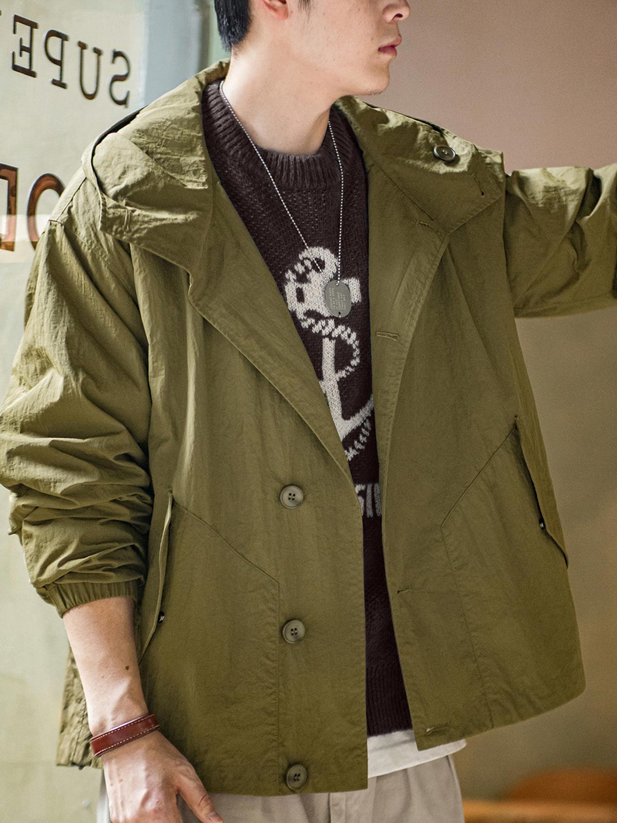 詳細画像
スタンドカラーと折り襟の2WAY仕様、エポレットディテール、フラップ付きスナップボタンポケット、そしてドローコード付き裾のディテールを強調したクローズアップ画像。機能性とデザイン性が融合した細部。
モデル画像
リラックス感のあるオーバーサイズシルエットのヴィンテージフード付きジャケットを着用し、アウトドアコーディネートを演出したモデル画像。軽量で耐久性のあるデザインが際立つスタイル。