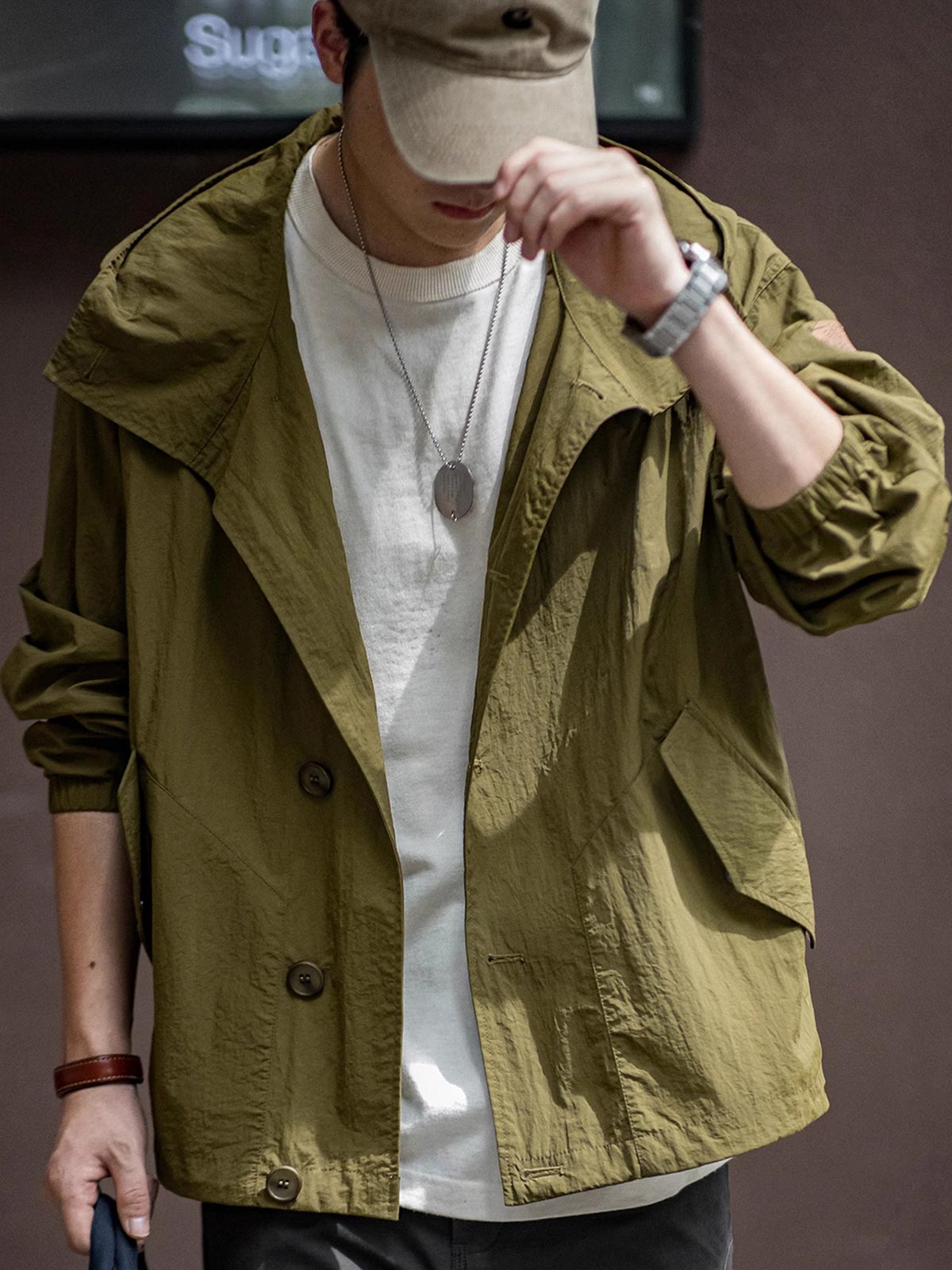 詳細画像
スタンドカラーと折り襟の2WAY仕様、エポレットディテール、フラップ付きスナップボタンポケット、そしてドローコード付き裾のディテールを強調したクローズアップ画像。機能性とデザイン性が融合した細部。
モデル画像
リラックス感のあるオーバーサイズシルエットのヴィンテージフード付きジャケットを着用し、アウトドアコーディネートを演出したモデル画像。軽量で耐久性のあるデザインが際立つスタイル。