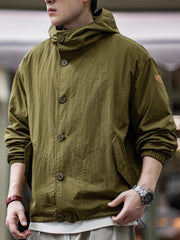 詳細画像
スタンドカラーと折り襟の2WAY仕様、エポレットディテール、フラップ付きスナップボタンポケット、そしてドローコード付き裾のディテールを強調したクローズアップ画像。機能性とデザイン性が融合した細部。
モデル画像
リラックス感のあるオーバーサイズシルエットのヴィンテージフード付きジャケットを着用し、アウトドアコーディネートを演出したモデル画像。軽量で耐久性のあるデザインが際立つスタイル。