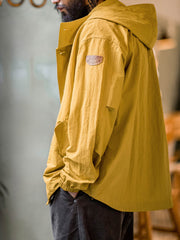 詳細画像
スタンドカラーと折り襟の2WAY仕様、エポレットディテール、フラップ付きスナップボタンポケット、そしてドローコード付き裾のディテールを強調したクローズアップ画像。機能性とデザイン性が融合した細部。
モデル画像
リラックス感のあるオーバーサイズシルエットのヴィンテージフード付きジャケットを着用し、アウトドアコーディネートを演出したモデル画像。軽量で耐久性のあるデザインが際立つスタイル。