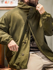 詳細画像
スタンドカラーと折り襟の2WAY仕様、エポレットディテール、フラップ付きスナップボタンポケット、そしてドローコード付き裾のディテールを強調したクローズアップ画像。機能性とデザイン性が融合した細部。
モデル画像
リラックス感のあるオーバーサイズシルエットのヴィンテージフード付きジャケットを着用し、アウトドアコーディネートを演出したモデル画像。軽量で耐久性のあるデザインが際立つスタイル。