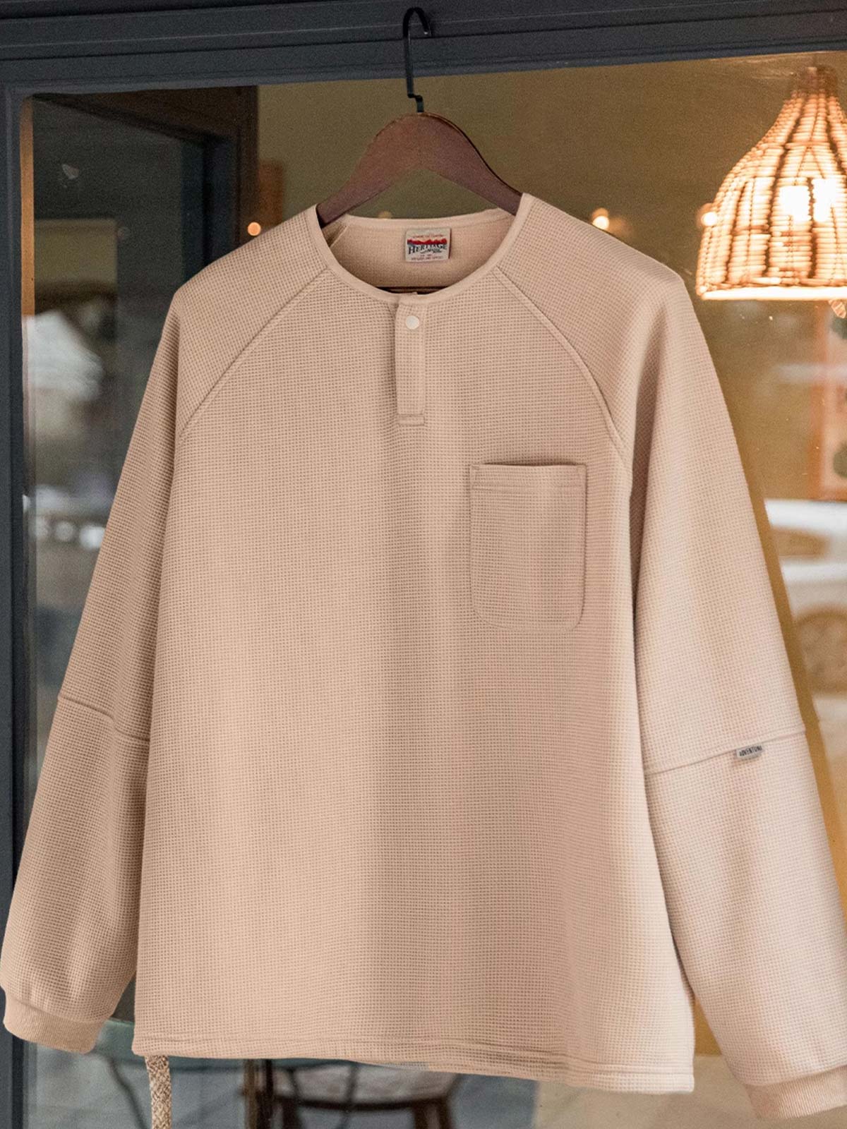 製品画像
立体感のあるワッフル編み素材を採用したヘンリーネックシャツの全体画像。ヴィンテージ感あふれるY字型ボタン付きデザインが特徴で、日常のカジュアルコーデやレイヤードスタイルにも最適。
詳細画像
幾何学模様のワッフル編みテクスチャー、袖口のリブディテール、裾のドローストリングデザインを強調したクローズアップ画像。ラグランスリーブと切り替えデザインが動きと立体感を演出。