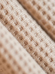 製品画像
立体感のあるワッフル編み素材を採用したヘンリーネックシャツの全体画像。ヴィンテージ感あふれるY字型ボタン付きデザインが特徴で、日常のカジュアルコーデやレイヤードスタイルにも最適。
詳細画像
幾何学模様のワッフル編みテクスチャー、袖口のリブディテール、裾のドローストリングデザインを強調したクローズアップ画像。ラグランスリーブと切り替えデザインが動きと立体感を演出。