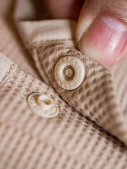 製品画像
立体感のあるワッフル編み素材を採用したヘンリーネックシャツの全体画像。ヴィンテージ感あふれるY字型ボタン付きデザインが特徴で、日常のカジュアルコーデやレイヤードスタイルにも最適。
詳細画像
幾何学模様のワッフル編みテクスチャー、袖口のリブディテール、裾のドローストリングデザインを強調したクローズアップ画像。ラグランスリーブと切り替えデザインが動きと立体感を演出。