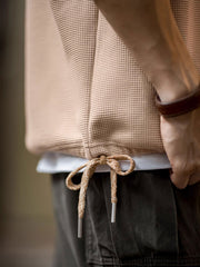 製品画像
立体感のあるワッフル編み素材を採用したヘンリーネックシャツの全体画像。ヴィンテージ感あふれるY字型ボタン付きデザインが特徴で、日常のカジュアルコーデやレイヤードスタイルにも最適。
詳細画像
幾何学模様のワッフル編みテクスチャー、袖口のリブディテール、裾のドローストリングデザインを強調したクローズアップ画像。ラグランスリーブと切り替えデザインが動きと立体感を演出。