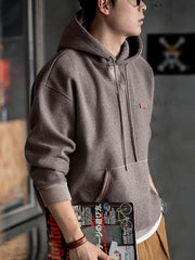 詳細画像
表面の細かい起毛デザインと、エンボスレザーラベル、袖口のリブ編みディテールが特徴。フードのドローコードと広めのポケットで、実用性とレトロなレイヤード感が強調されています。ダブルファブリックのミックス刺し毛加工が肌触りと保温性を向上。
モデル画像
冬のコーディネートに最適なウール混フード付きパーカーを着用したモデル。起毛デザインとレトロなディテールが際立ち、快適さと保温性を提供。