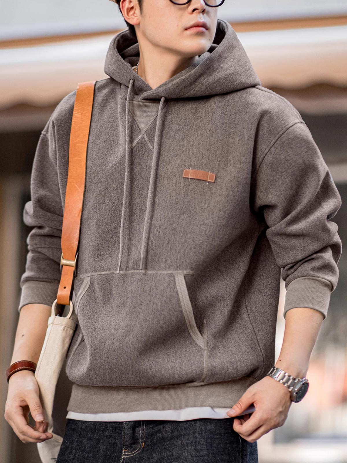 詳細画像
表面の細かい起毛デザインと、エンボスレザーラベル、袖口のリブ編みディテールが特徴。フードのドローコードと広めのポケットで、実用性とレトロなレイヤード感が強調されています。ダブルファブリックのミックス刺し毛加工が肌触りと保温性を向上。
モデル画像
冬のコーディネートに最適なウール混フード付きパーカーを着用したモデル。起毛デザインとレトロなディテールが際立ち、快適さと保温性を提供。