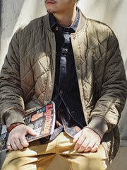 詳細画像: キルティングベースボールジャケットのステッチポケットとオレンジ色の手刺繍風ディテールのクローズアップ。銅製スナップボタンのディテールと、均等に分布した中綿が暖かさを保証。
モデル画像: モデルがキルティングベースボールジャケットデザイン中綿ジャケットを着用している画像。レトロなスタイルと現代的な技術を融合したデザインで、秋冬のカジュアルコーディネートにぴったり。