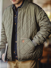 詳細画像: キルティングベースボールジャケットのステッチポケットとオレンジ色の手刺繍風ディテールのクローズアップ。銅製スナップボタンのディテールと、均等に分布した中綿が暖かさを保証。
モデル画像: モデルがキルティングベースボールジャケットデザイン中綿ジャケットを着用している画像。レトロなスタイルと現代的な技術を融合したデザインで、秋冬のカジュアルコーディネートにぴったり。