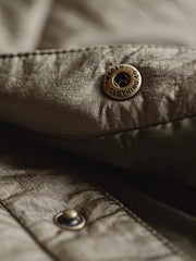 製品画像: レトロなキルティングベースボールジャケットデザイン中綿ジャケット正面展示画像。クラシックなベースボールジャケットのシルエットに、精緻なキルティング技術とオレンジ色の手刺繍ディテールが特徴。光沢ナイロン素材とポリエステル繊維で暖かさとスタイルを提供します。
詳細画像: キルティングベースボールジャケットのステッチポケットとオレンジ色の手刺繍風ディテールのクローズアップ。銅製スナップボタンのディテールと、均等に分布した中綿が暖かさを保証。