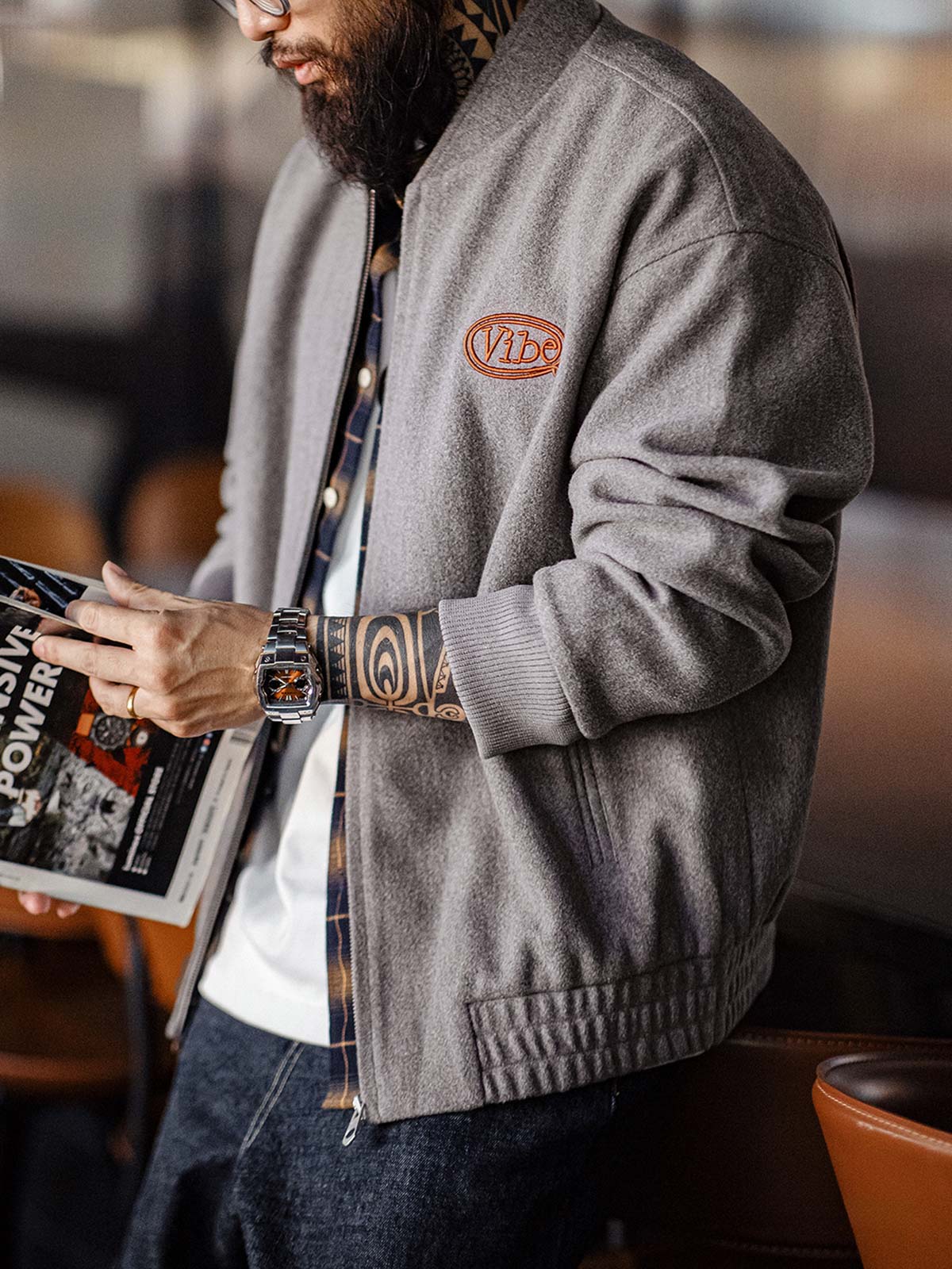 詳細画像:
"アメカジグラフィティ要素を取り入れた立体刺繍と、背面の牛革紙ラベルのディテールクローズアップ。袖口と裾のリブ編みがヴィンテージ感と着心地の良さを強調"
モデル画像:
"アメカジヴィンテージスタイルのウール混紡ベースボールジャケットを着用した、日常のトレンドコーディネート。リブ編みの袖口と裾がアクセントになったカジュアルスタイル"