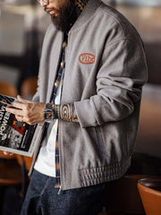 詳細画像:
"アメカジグラフィティ要素を取り入れた立体刺繍と、背面の牛革紙ラベルのディテールクローズアップ。袖口と裾のリブ編みがヴィンテージ感と着心地の良さを強調"
モデル画像:
"アメカジヴィンテージスタイルのウール混紡ベースボールジャケットを着用した、日常のトレンドコーディネート。リブ編みの袖口と裾がアクセントになったカジュアルスタイル"